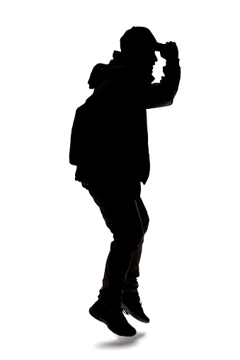 Silhouette of a male hiker or explorer isolated on a white background wearing a hat and clothes for trekking. He is leaping or jumping
