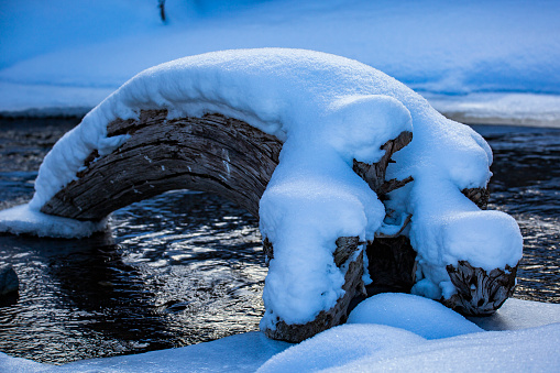 A snow covered log over a stream