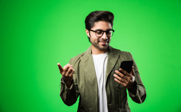 istock Indian / Asian man with smartphone, standing isolated over green background 1198566722