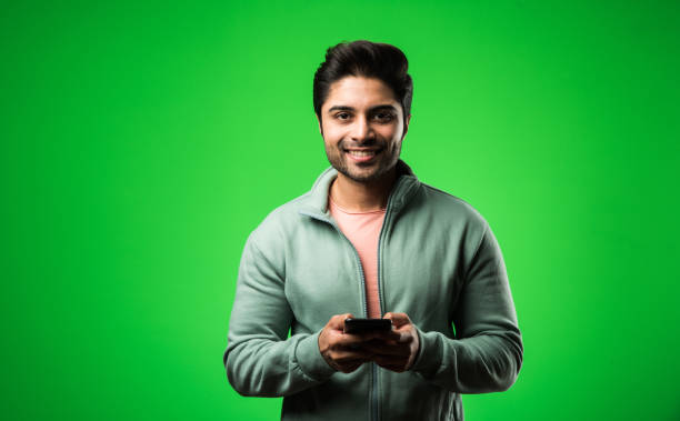 istock Indian / Asian man with smartphone, standing isolated over green background 1198566775