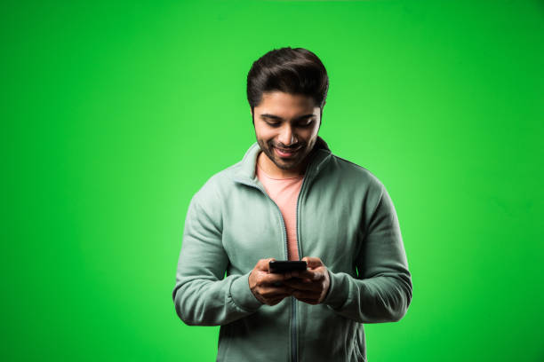 istock Indian / Asian man with smartphone, standing isolated over green background 1198567920