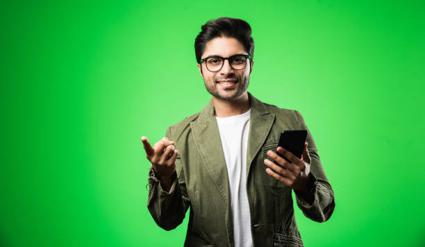 istock Indian / Asian man with smartphone, standing isolated over green background 1198567927