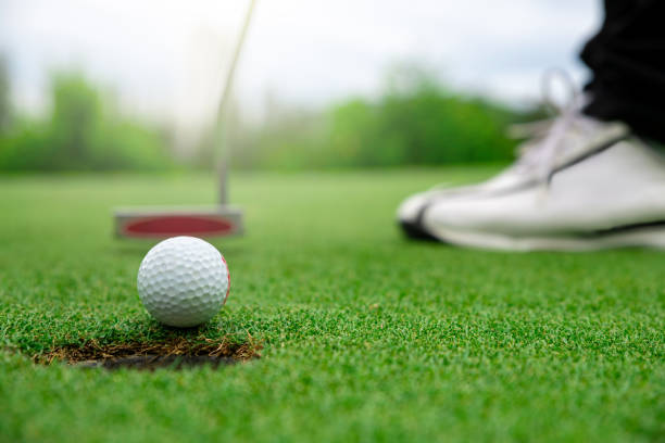 nahaufnahme des golfballs auf dem grünen rasenplatz - golf power golf course challenge stock-fotos und bilder