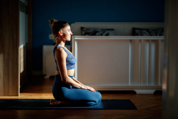 meditating at home - yoga meditating women exercise mat imagens e fotografias de stock