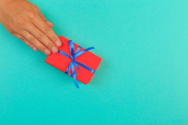 istock gift in female hands on a colored background top view. 1198578212