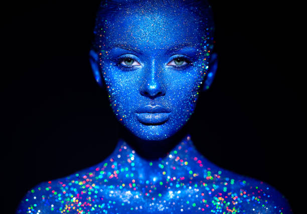 Portrait of beautiful woman with sparkles on her face Fashion model woman in blue bright sparkles and neon lights posing in studio.  Portrait of beautiful sexy woman. Art design colorful glitter glowing make up body paint stock pictures, royalty-free photos & images
