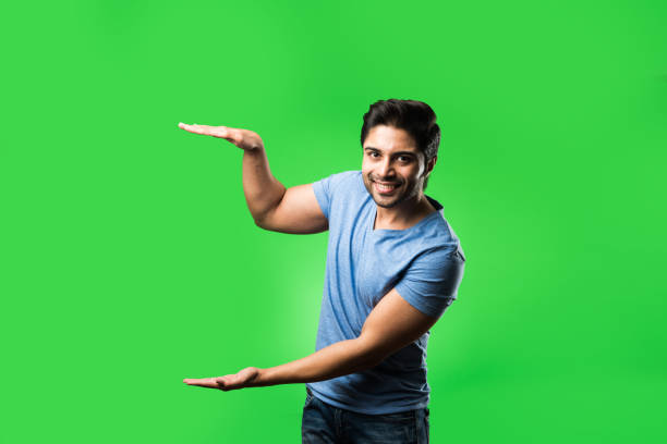 istock satisfied Indian Man presenting, pointing, displaying or advertising with empty hands or fingers. standing isolated over green background 1198582716