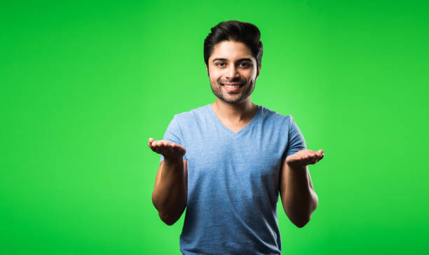 istock satisfied Indian Man presenting, pointing, displaying or advertising with empty hands or fingers. standing isolated over green background 1198583396