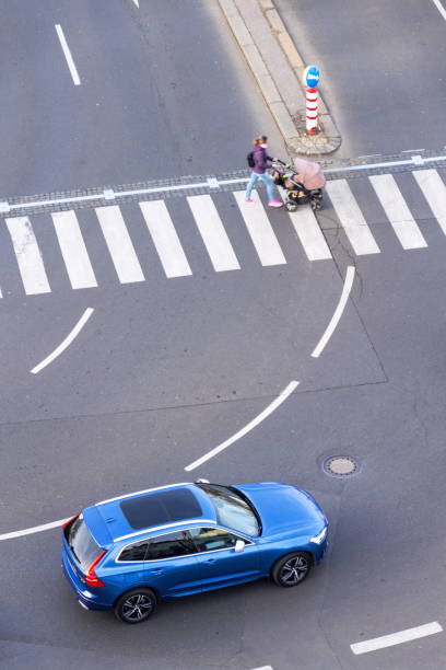 Blue car heading to pedestrian crossing with unrecognizable young woman pushing baby carriage, safety of self-driving autonomous technology concept, aerial birds eye view Prague, Czech Republic - March 6, 2019: Blue car heading to pedestrian crossing with unrecognizable young woman pushing baby carriage on March 6, 2019 in Prague, Czech Republic. buggy eyes stock pictures, royalty-free photos & images