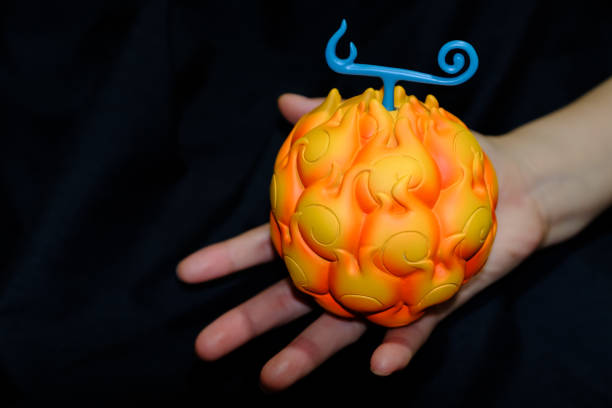 orange color toy fruit model display in hand on black background
