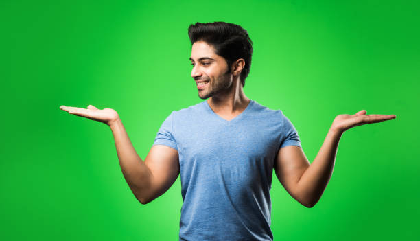 istock satisfied Indian Man presenting, pointing, displaying or advertising with empty hands or fingers. standing isolated over green background 1198583964