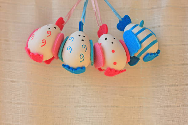 Easter holiday concept with cute handmade eggs, chicks with felt wings, tail and tuft. Funny chickens with stripes and dots. Blue boys eggs and pink girls eggs.