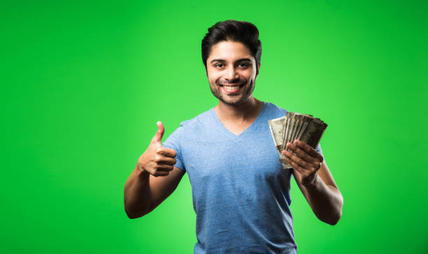 Indian happy man with money fan, standing isolated against green chroma screen Indian happy man with money fan, standing isolated against green chroma screen save man india stock pictures, royalty-free photos & images