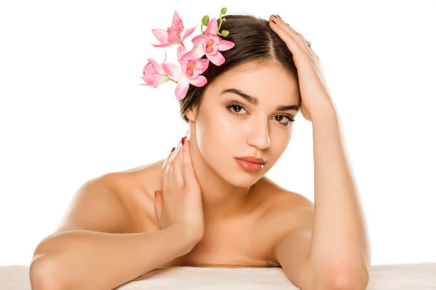 istock Young woman with makeup  posing with orchids on white background 1198585164