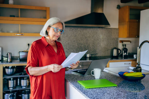 istock Senior woman reading documents in domestic kitchen 1198585729