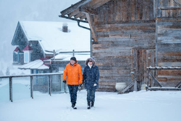 알파인 마운틴 스키 리조트에서 눈 속에서 걷는 행복한 활동적인 은퇴 자 커플 - ski resort village austria winter 뉴스 사진 이미지