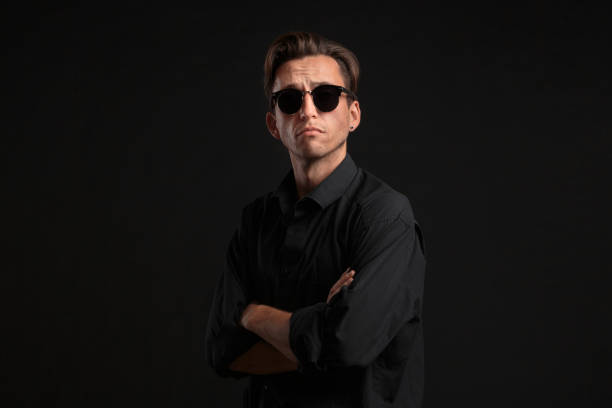 istock Confident stylish man in black eyeglasses isolated over black background. 1198588990