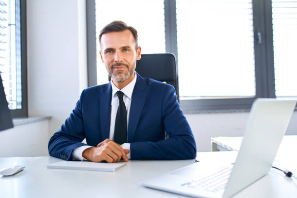 미소 성숙한 사업가 앉아 에 사무실 책상 보고 카메라 - business person sitting looking at camera corporate business 뉴스 사진 이미지