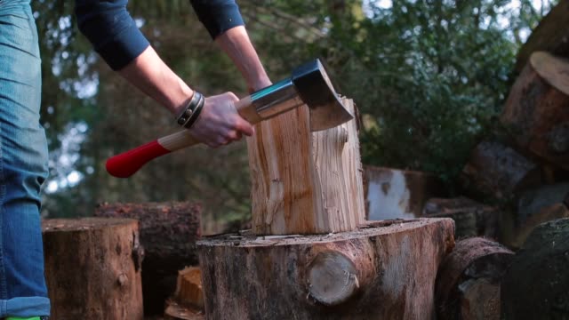 A lumberjack makes light hits on a wooden block with an ax.