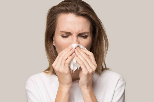istock Sick young woman use tissue blowing runny nose 1198590567