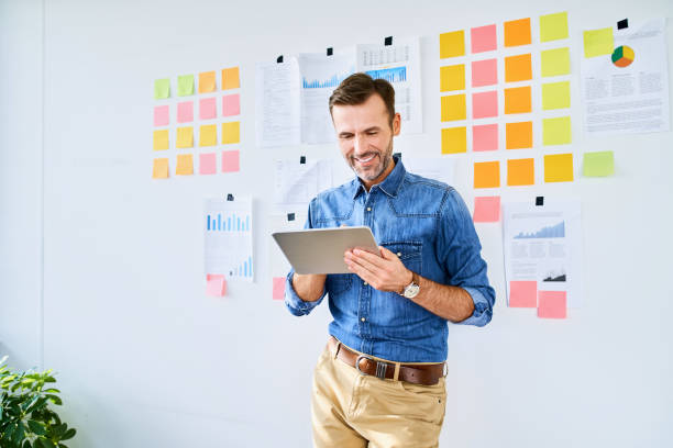 istock Portrait of office worker using tablet and leaning against office wall 1198591273