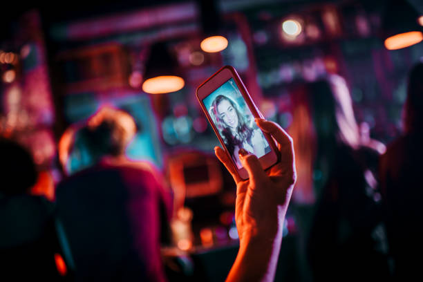 istock Young millennial female using her smart phone to take a selfie in a bar 1198593849