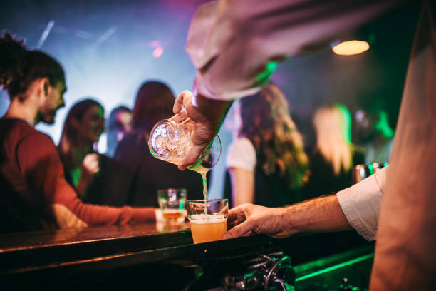 istock Bartender pouring drinks into shot glasses from a drink shaker in a pub 1198594031