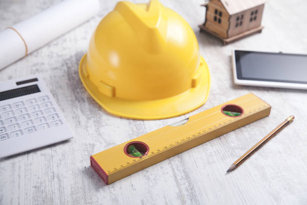 istock Wooden house model with a helmet, tablet and other objects. 1198595327
