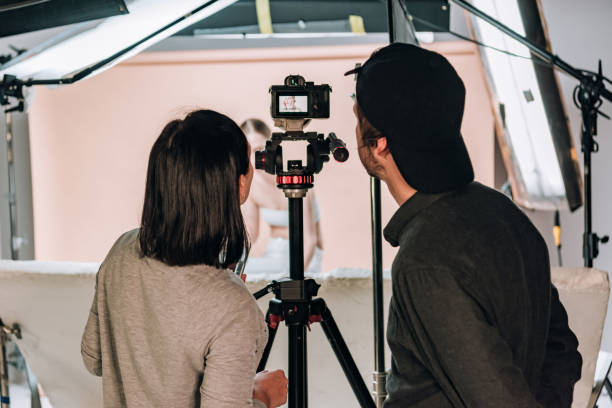 istock Rear view of cameraman and assistant looking at camera display while working with woman in photo studio 1198596865
