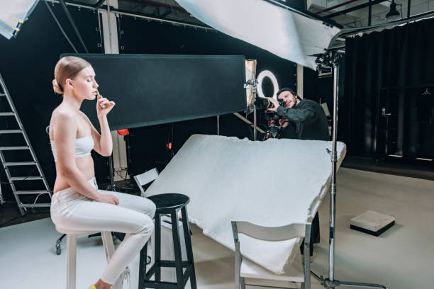 istock Beautiful model posing with massage roller for videographer in photo studio with spotlights 1198596869