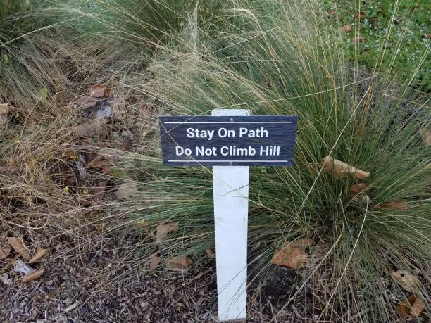 istock stay on path do not climb hill sign with grasses 1198597294