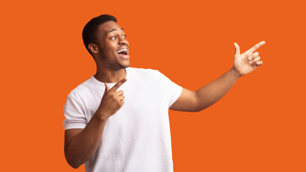 istock Excited black guy pointing two fingers aside 1198604303