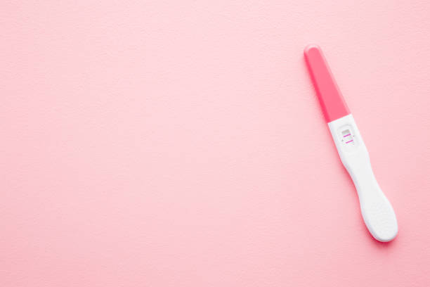 istock Pregnancy test with two stripes on light pastel pink background. Positive result. Closeup. Empty place for text. Top down view. 1198605967