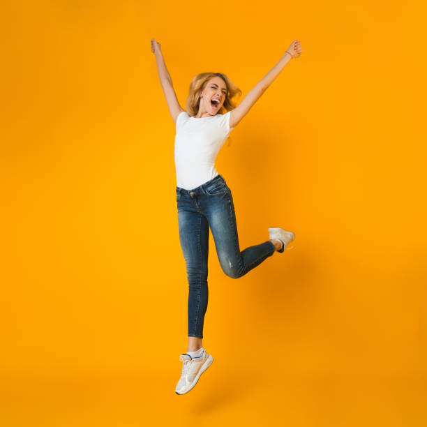 istock Going crazy. Woman jumping and shouting on orange background 1198605975