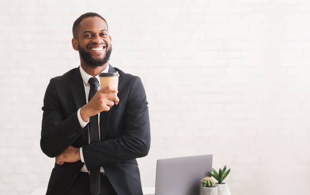 istock Handsome cheerful african businessman drinking coffee over white wall 1198607955