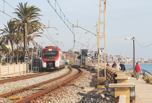 Renfe Cercanías train approaching and passerby in the promenade