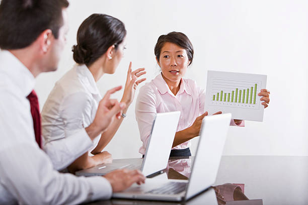 istock Asian businesswoman presenting graph to co-workers in office boa 119861011