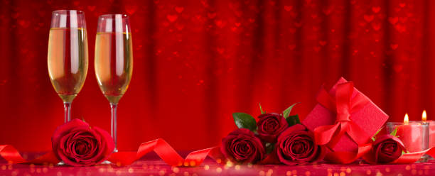istock Celebration dinner concept. Champagne glasses, gift package and roses on table 1198611303