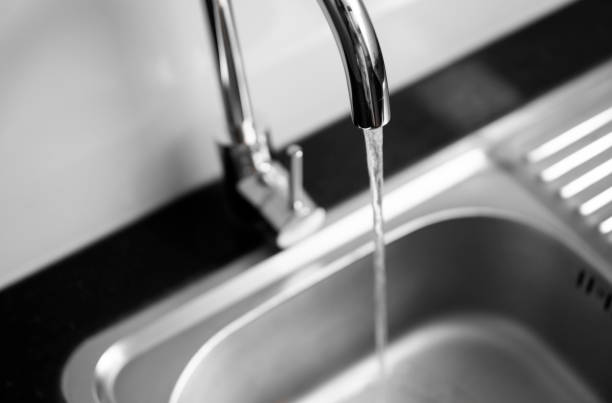 Close up on modern kitchen metal faucet and metal kitchen sink with a running water. stock photo