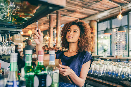 Cropped shot of a young woman counting stock in a bar