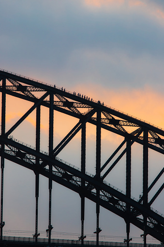 Silhouette of people climbing the Sydney Harbour Bridge in the morning.