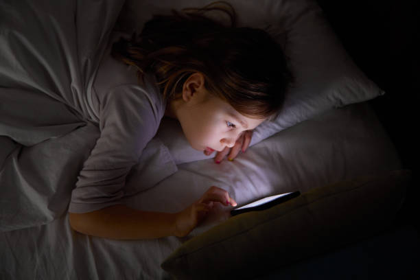 istock little girl on bed touching mobile phone at night 1198614073