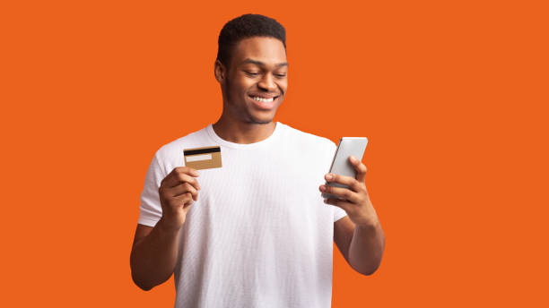 istock Black guy holding credit card and smartphone 1198614850