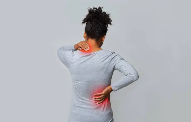 Photo of Back view of afro woman rubbing her neck and loins