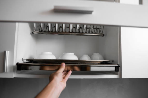 istock Dish drying metal rack with big nice white clean plates. Traditional comfortable kitchen. Open white dish draining closet with wet dishes of glass and ceramic, plates, bowls drying inside on rack. 1198616291