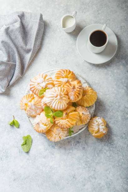 istock Profiterole or gougeres or eclair with custard cream filling served for breakfast on a white plate with tea on a concrete table, view from above, close-up 1198616914
