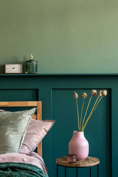 istock Modern bedroom interior with design coffee table, flowers in vase and elegant personal accessories. Beautiful bed sheets, blanket and pillows. Template. Stylish home staging. Wall panelling. Details 1198617004