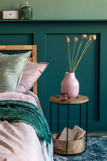 istock Modern bedroom interior with design coffee table, flowers in vase and elegant personal accessories. Beautiful bed sheets, blanket and pillows. Template. Stylish home staging. Wall panelling. Details 1198617106