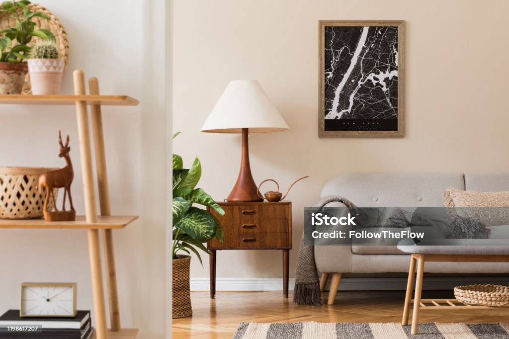 Modern composition of living room interior with brown mock up poster frame, design retro commode, sofa, bookstand, rattan basket with plant and elegant accessories. Template. Stylish home staging. Design scandinavian home interior of living room.Beige wall. Modern home staging. Template. Japandi. Home Interior Stock Photo