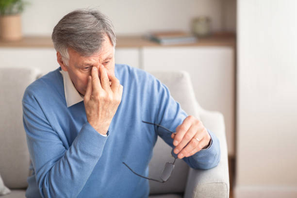 istock Senior Man Massaging Nosebridge Sitting On Sofa, Selective Focus 1198617306